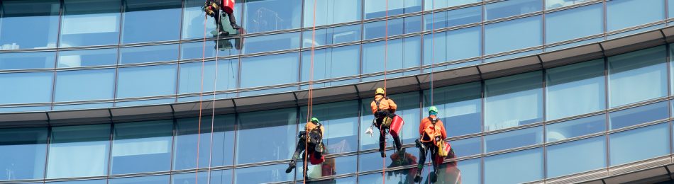 Window cleaners suspended on the side of a skyscraper cleaning the office windows looking up from below