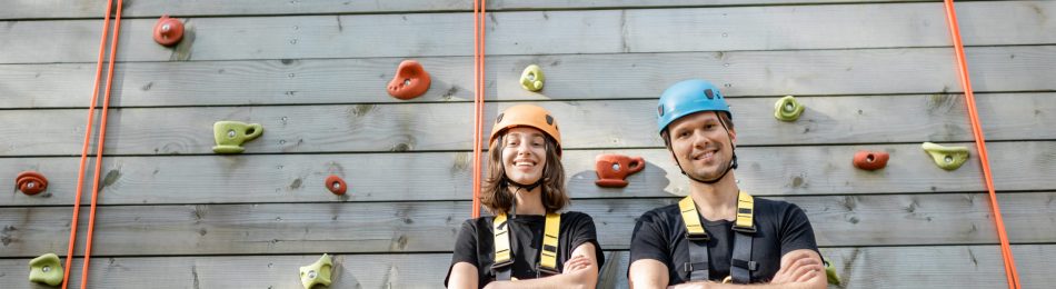 Portrait of an active well-equipped couple ready to climb the wall at the amusement park outdoors